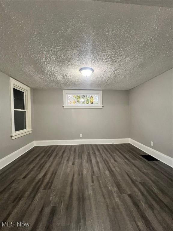 basement with baseboards, dark wood-type flooring, and a textured ceiling