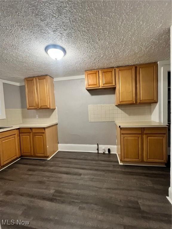 kitchen featuring decorative backsplash, dark wood-style floors, and brown cabinets