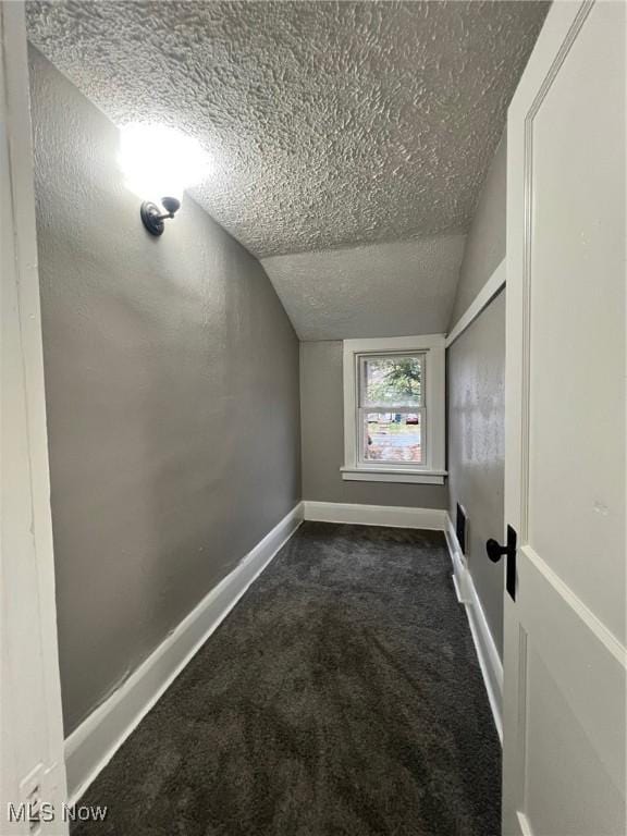 unfurnished room with baseboards, a textured ceiling, lofted ceiling, and carpet floors