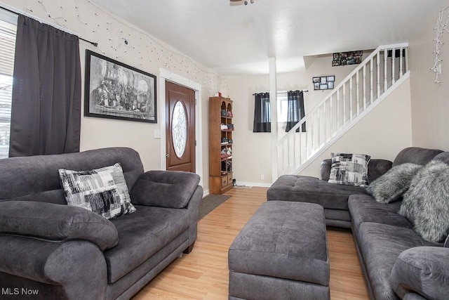 living area with stairway, light wood-style flooring, and baseboards