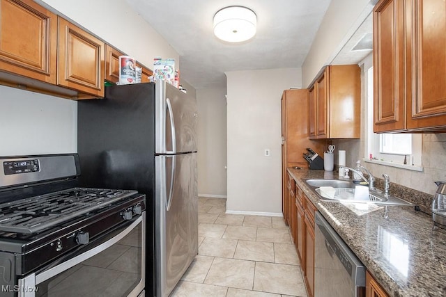 kitchen with a sink, baseboards, brown cabinets, and appliances with stainless steel finishes