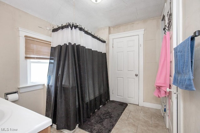 full bath with tile patterned floors, curtained shower, and baseboards