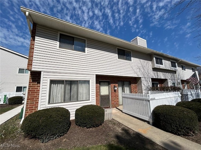 townhome / multi-family property with brick siding and a chimney