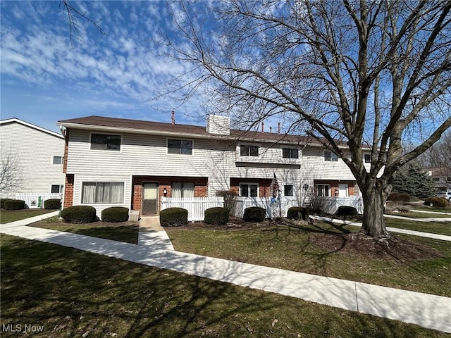 townhome / multi-family property featuring a chimney and a front lawn