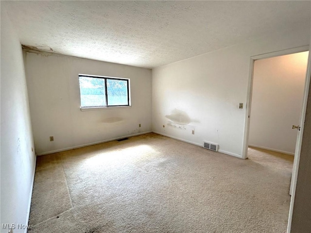 carpeted empty room with visible vents, a textured ceiling, and baseboards