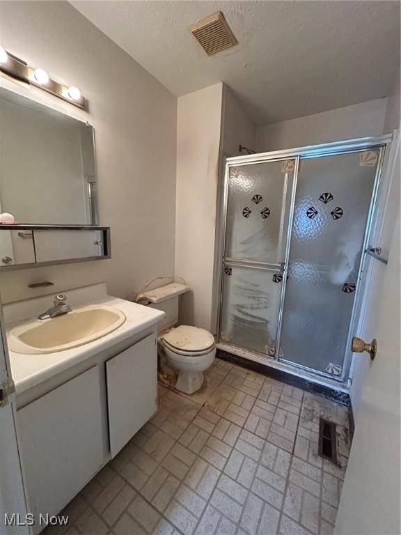 bathroom with vanity, a shower stall, toilet, and visible vents