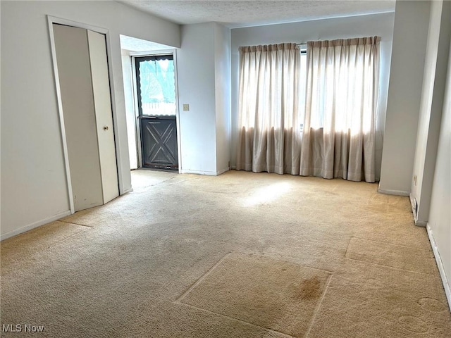 carpeted spare room with baseboards and a textured ceiling