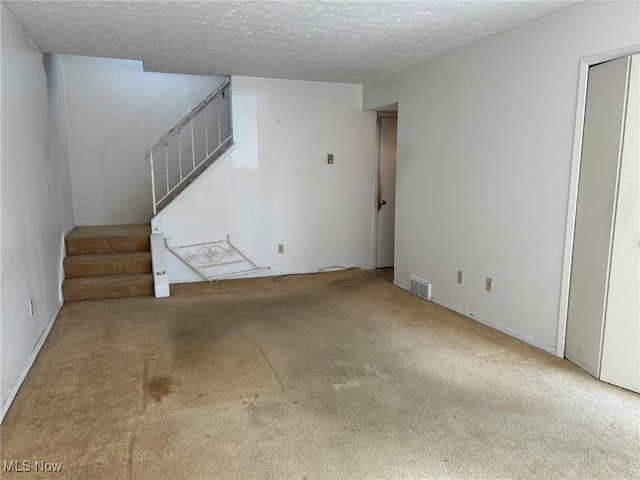 unfurnished living room featuring visible vents, carpet, stairs, and a textured ceiling