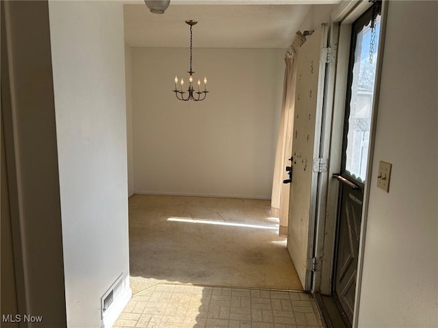 corridor with tile patterned floors, a notable chandelier, and carpet flooring