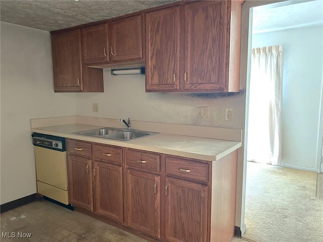 kitchen featuring dishwashing machine, brown cabinetry, baseboards, a sink, and light countertops