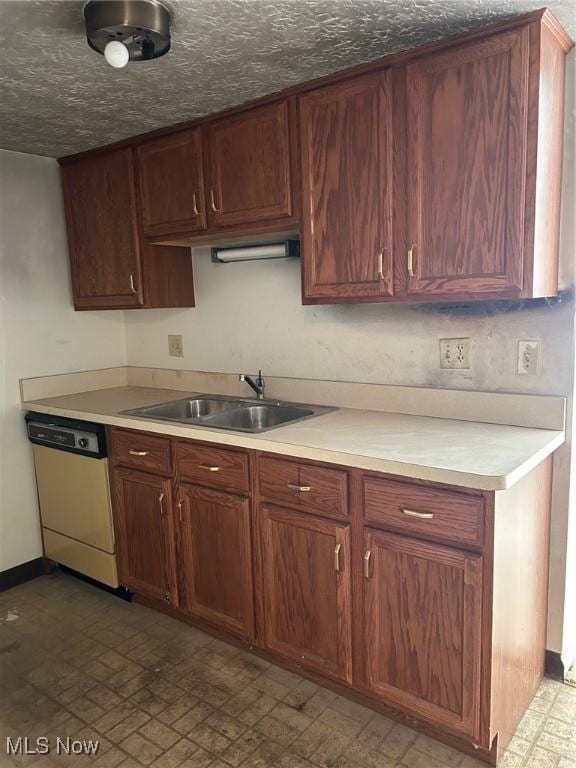 kitchen with dishwashing machine, light countertops, baseboards, and a sink