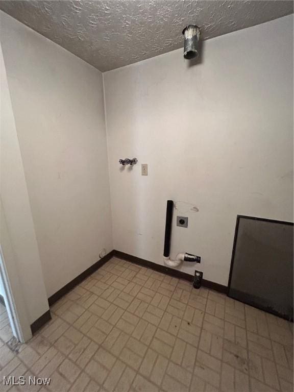 laundry room with baseboards, hookup for an electric dryer, laundry area, and a textured ceiling