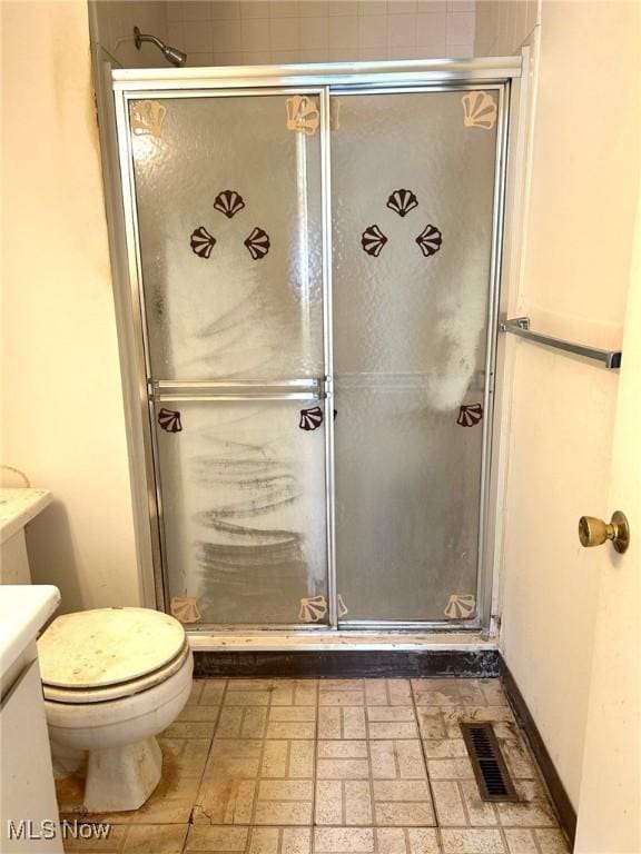 full bath with visible vents, toilet, a shower stall, baseboards, and vanity