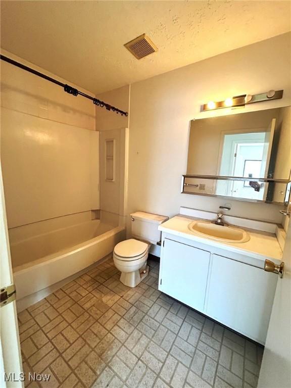 full bath with visible vents, toilet, vanity, bathing tub / shower combination, and a textured ceiling