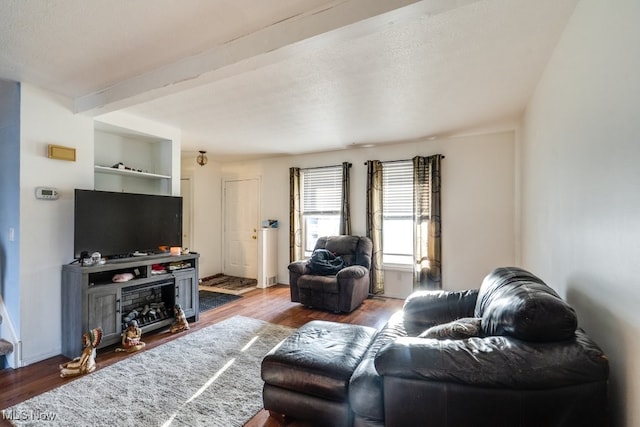 living area featuring beam ceiling, baseboards, and wood finished floors