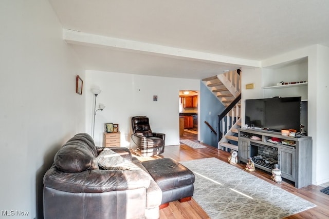 living room with beam ceiling, stairs, and wood finished floors