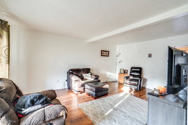 living area featuring beamed ceiling and wood finished floors