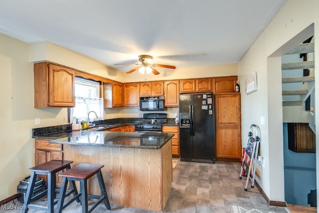 kitchen featuring brown cabinets, a peninsula, black appliances, and a sink