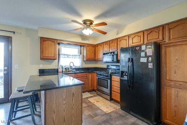 kitchen featuring brown cabinets, black appliances, a sink, a peninsula, and a breakfast bar area