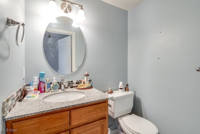 bathroom with decorative backsplash, toilet, and vanity