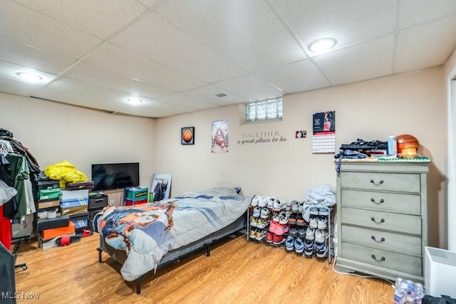 bedroom with a paneled ceiling and wood finished floors