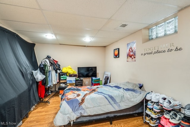 bedroom with visible vents, a paneled ceiling, and wood finished floors