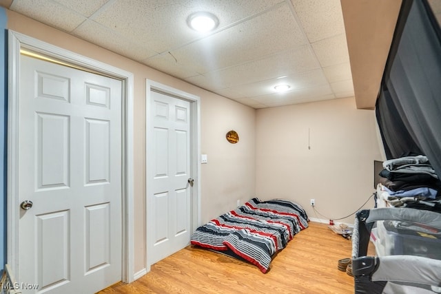 bedroom featuring baseboards, a paneled ceiling, and wood finished floors