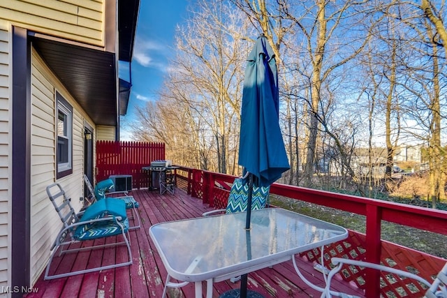 wooden deck with outdoor dining space, cooling unit, and grilling area