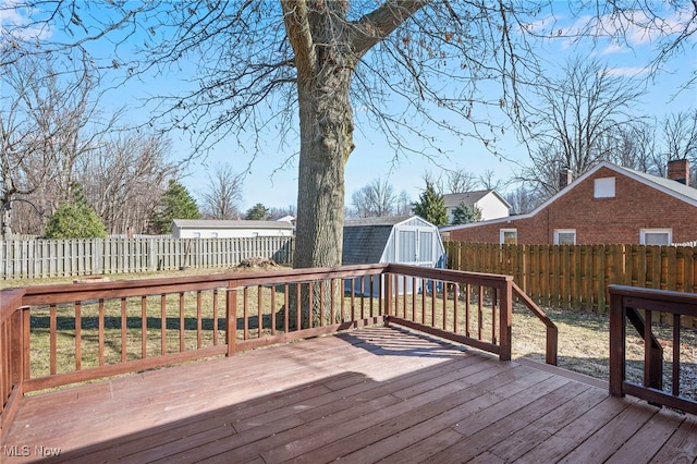 wooden deck with a storage shed, an outbuilding, and a fenced backyard