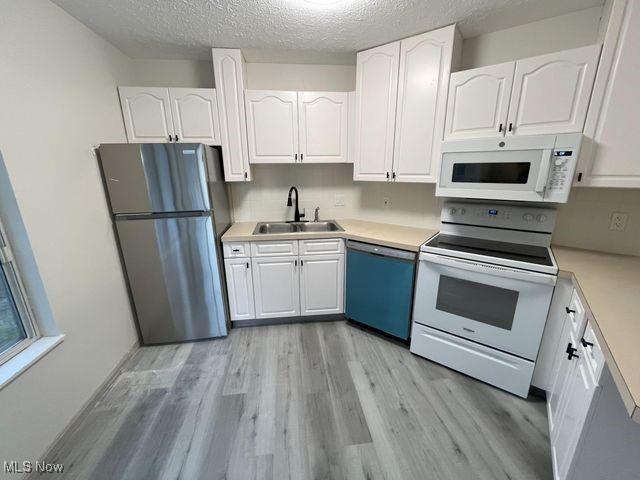 355 Village Pointe Dr Unit 1-A, Akron, OH 44313 - kitchen with white appliances, light wood finished floors, a sink, light countertops, and white cabinets