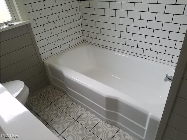 bathroom featuring tile patterned flooring, toilet, and a tub