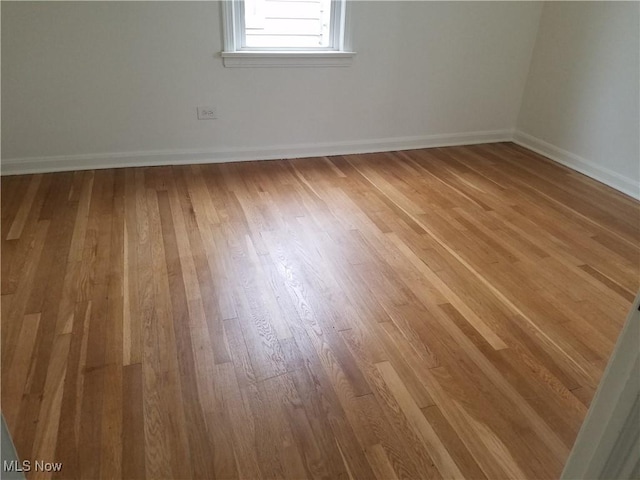 spare room with baseboards and wood finished floors