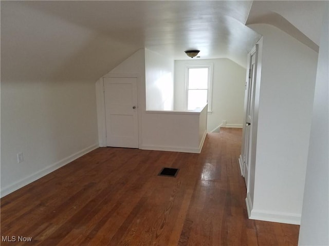 additional living space with visible vents, lofted ceiling, baseboards, and wood finished floors