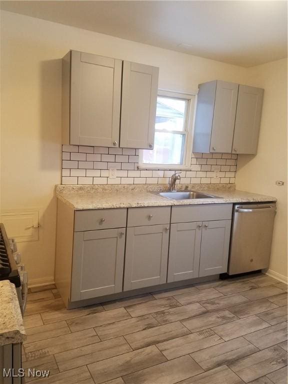 kitchen with tasteful backsplash, a sink, gray cabinetry, and stainless steel dishwasher