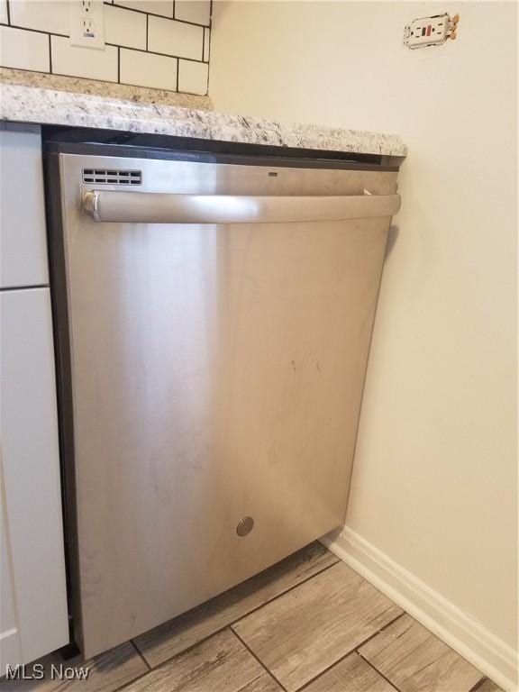 interior details featuring wood finish floors, decorative backsplash, baseboards, and stainless steel dishwasher