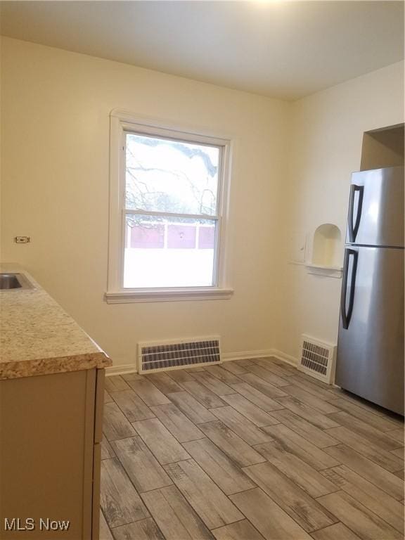 kitchen with visible vents, light wood finished floors, light countertops, and freestanding refrigerator