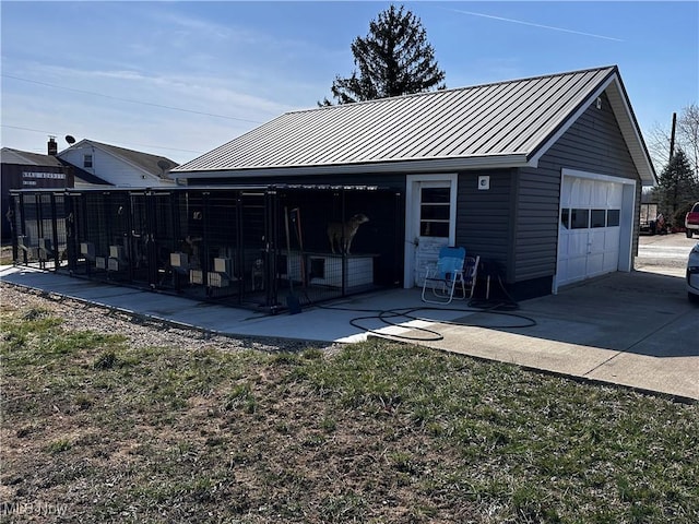 back of property featuring driveway, a standing seam roof, a patio, metal roof, and a garage