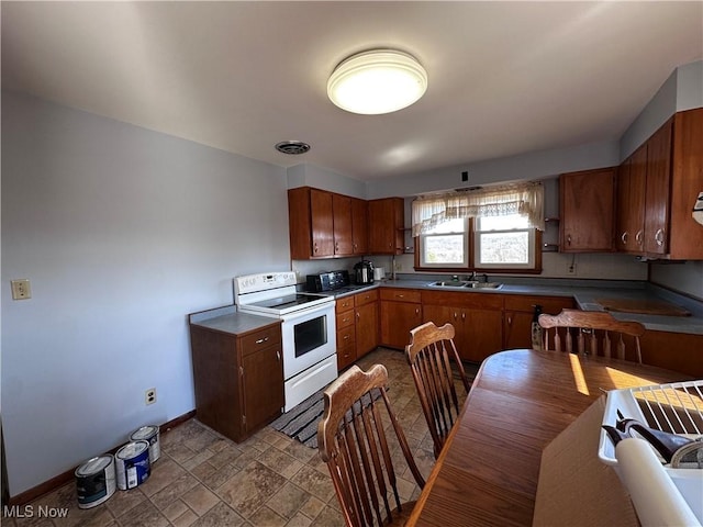 kitchen featuring visible vents, baseboards, white electric range oven, stone finish floor, and a sink