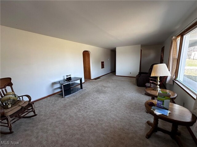 sitting room with baseboards, arched walkways, and carpet floors