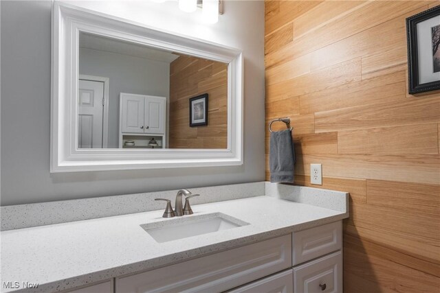 bathroom featuring wooden walls and vanity