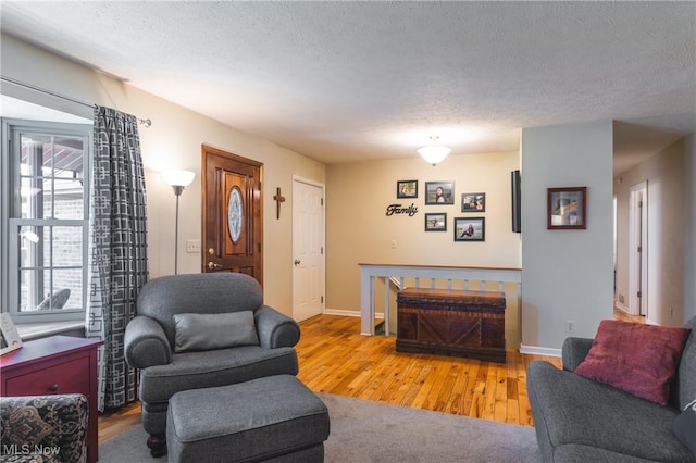 living area with wood finished floors, baseboards, and a textured ceiling