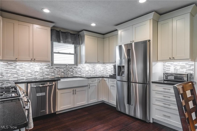 kitchen featuring dark wood-type flooring, a sink, backsplash, recessed lighting, and stainless steel appliances