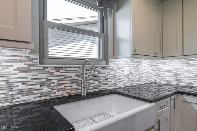 kitchen featuring a sink, tasteful backsplash, gray cabinetry, and dark stone countertops