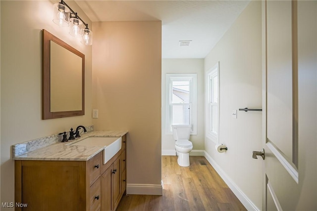 bathroom with visible vents, toilet, wood finished floors, baseboards, and vanity