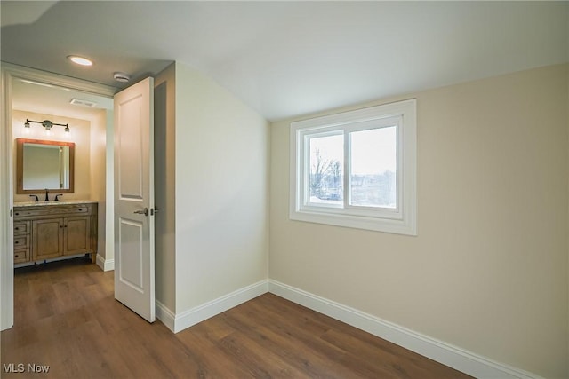 interior space featuring visible vents, lofted ceiling, a sink, baseboards, and dark wood-style flooring