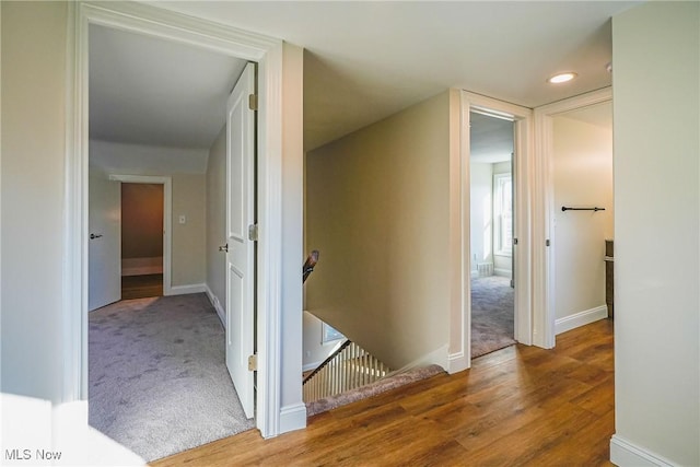 hall featuring an upstairs landing, carpet flooring, and baseboards