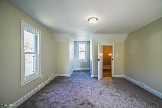 unfurnished bedroom featuring lofted ceiling, visible vents, baseboards, and carpet floors