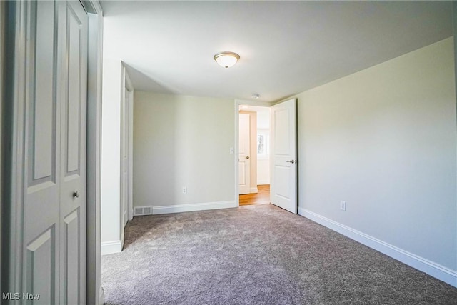 unfurnished bedroom with carpet, visible vents, and baseboards