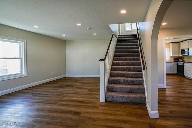 stairs featuring recessed lighting, baseboards, arched walkways, and wood finished floors