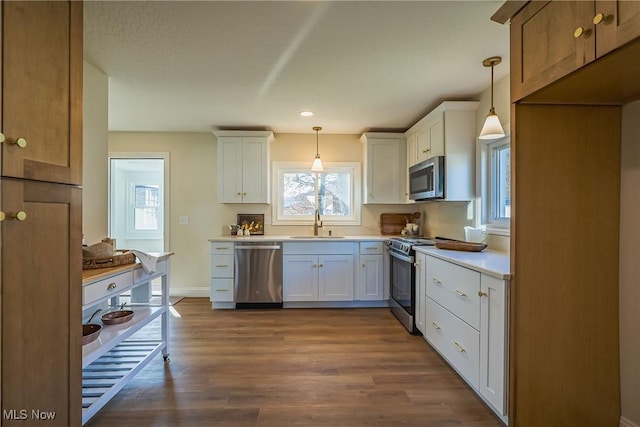 kitchen with a sink, stainless steel appliances, pendant lighting, and dark wood finished floors